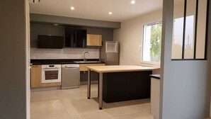 Una cocina moderna con horno empotrado, lavavajillas, pileta y ventana que proporciona luz natural.