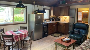 Una cocina acogedora con una mesa de comedor, sillas, refrigerador, estufa y pileta.