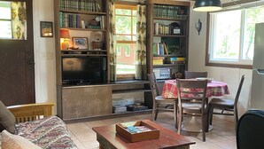 Una sala de estar acogedora con un sofá de madera, una mesita de centro y una estantería llena de libros.