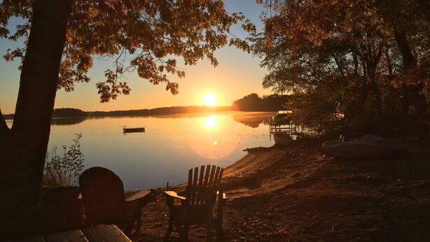 Vista del lago con un banco de madera y un bote amarrado en la orilla.