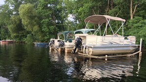 Un bote amarrado en un muelle con toldo, rodeado de árboles.