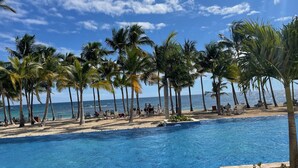 Un espace aménagé au bord de la piscine, avec des palmiers et une vue sur l’océan.