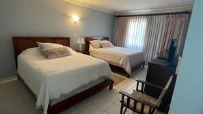 Ein Hotelzimmer mit zwei Betten, einem Schreibtisch und einem Stuhl.