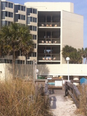 A multi-story building with balconies, a pathway leading to the entrance, and a sign indicating amenities. - Beachfront Studio, Free Beach Service included with stay (Panama City Beach)