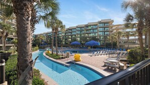 A swimming pool with lounge chairs and umbrellas, surrounded by palm trees and a multi-story hotel building. - Phoenix on the Bay 1412 by Liquid Life (Orange Beach)
