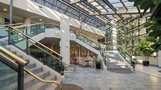 A multi-level atrium with glass railings, a central staircase, and seating areas. - Phoenix on the Bay 1412 by Liquid Life (Orange Beach)