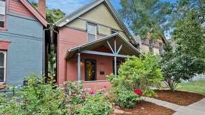 A two-story building with a red brick facade, a covered porch, and a stone pathway leading to the entrance. - Exceptional and artful, modern Victorian. Very centrally located. Dog friendly! (Denver)