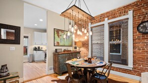 A dining area with a brick wall, a wooden ceiling, and a hanging light fixture. - Exceptional and artful, modern Victorian. Very centrally located. Dog friendly! (Denver)