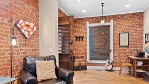A room with a brick wall, a leather armchair, a wooden guitar, and a globe on a table. - Exceptional and artful, modern Victorian. Very centrally located. Dog friendly! (Denver)