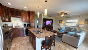 A spacious kitchen with granite countertops, wooden cabinets, and a central island with bar stools. - The Seahorse Suite.  Welcoming guests back to Ft Myers Beach!  2 bedroom, 2 bath (Fort Myers Beach)