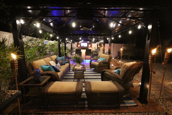 An outdoor lounge area with wicker furniture, a central coffee table, and ambient lighting.
