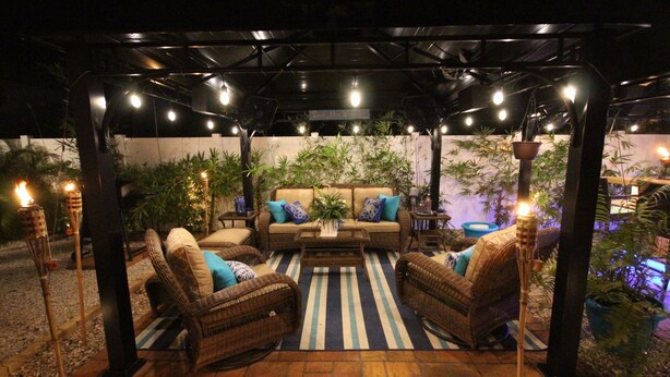 An outdoor patio with wicker furniture, a striped rug, and ambient lighting. - The Seahorse Suite.  Welcoming guests back to Ft Myers Beach!  2 bedroom, 2 bath (Fort Myers Beach)