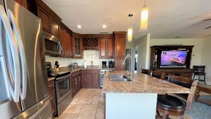 A modern kitchen with stainless steel appliances, a granite countertop, and a large island with bar stools. - The Seahorse Suite.  Welcoming guests back to Ft Myers Beach!  2 bedroom, 2 bath (Fort Myers Beach)