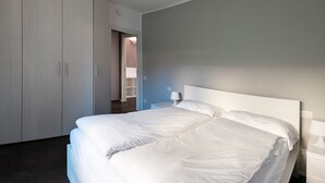 Een slaapkamer met een groot bed, een kledingkast en een nachtkastje met een lamp.