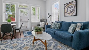 Un salon moderne avec un canapé bleu, une table basse et un coin repas comprenant des chaises et une table.
