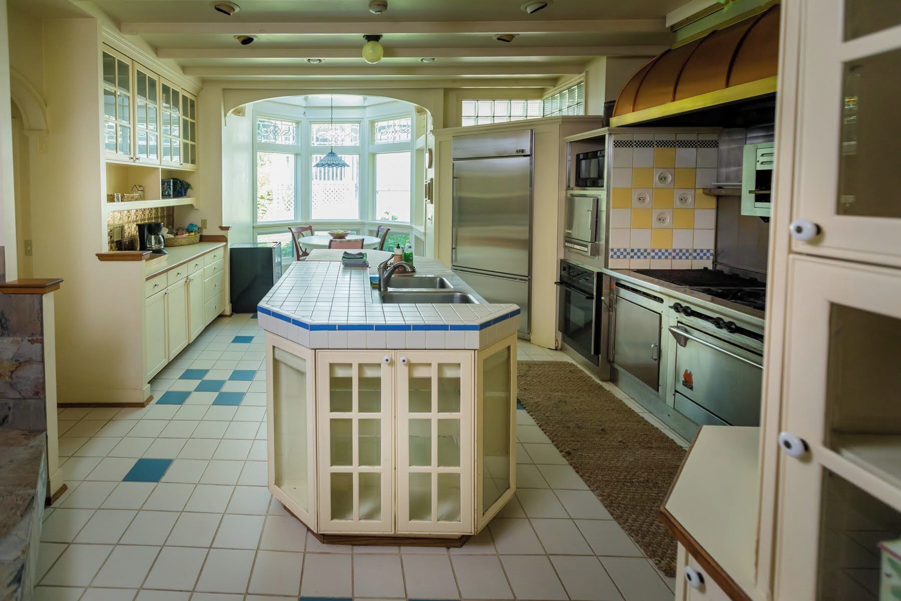 Una cucina con isola centrale, frigorifero, piano cottura e pensili.