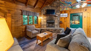 L’intérieur d’un chalet confortable, avec une cheminée en pierre, des murs en bois et une porte verte.