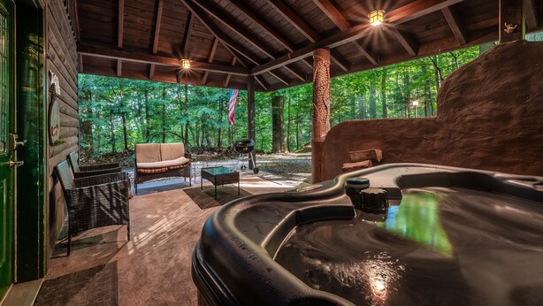 Une cabane en bois dotée d’un bain à remous, d’un espace salon extérieur et offrant une vue sur la forêt.