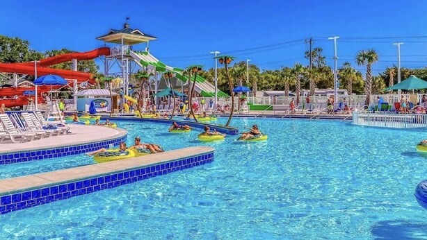 A water park with a pool, slides, and lounge areas.
