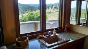 Cuina amb taulell de granit, un rentaplat i una finestra amb vista a un paisatge forestal.