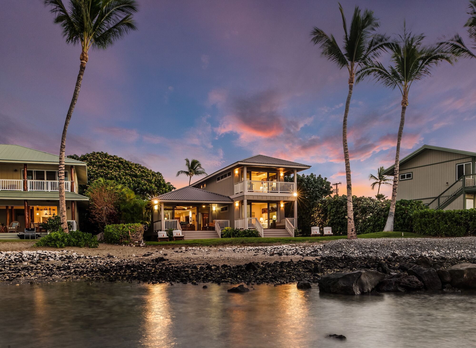A beachfront property with a two-story house, a covered patio, and a pool area.