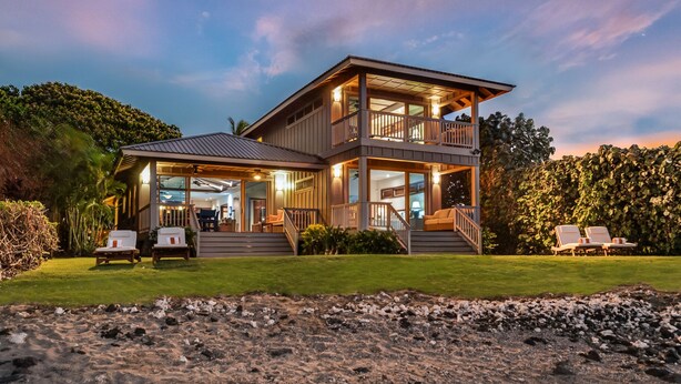 A two-story house with a balcony, a covered porch, and a view of the beach. - Serene 3BR Puako Estate P10D – Beachfront Access & Tranquil Living (Kamuela)