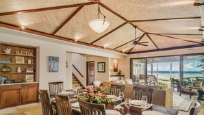 A dining area with a view of the ocean, wooden furniture, and a ceiling with a woven design. - Serene 3BR Puako Estate P10D – Beachfront Access & Tranquil Living (Kamuela)