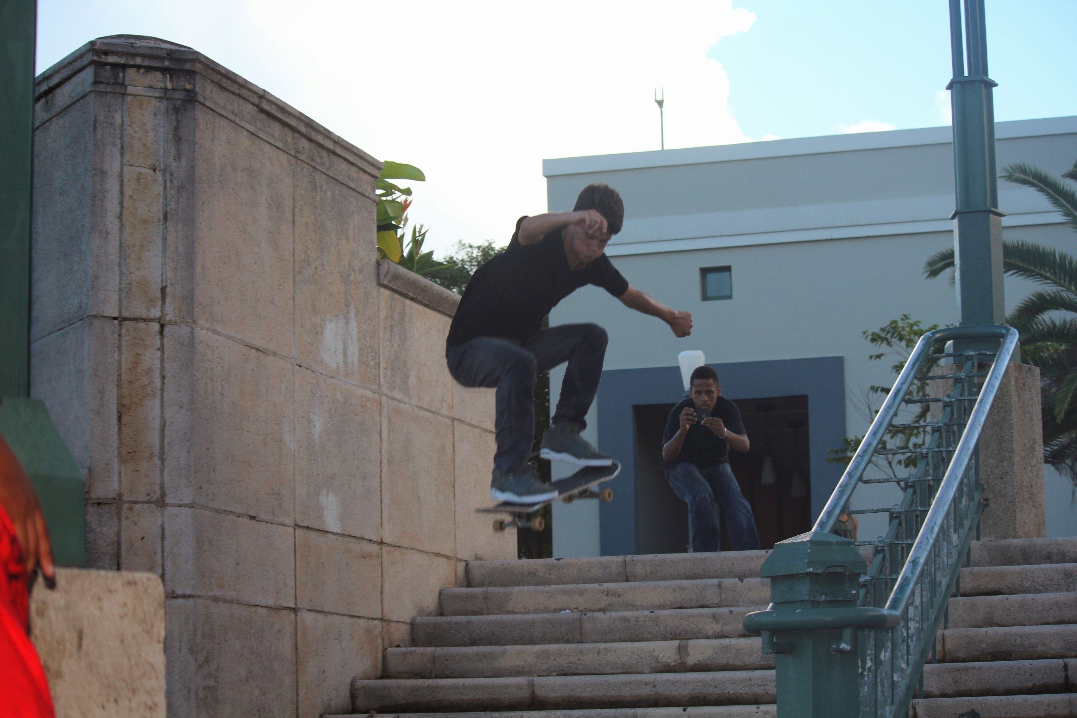 Una persona patina sobre una tabla por unas escaleras exteriores.