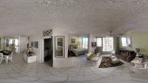 A spacious living room with a high ceiling, a dining area, and a bedroom visible through an open door. - FLASH SALE:  Beautiful Beach Front Location (Carolina, Isla Verde)
