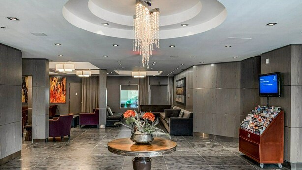 A modern lobby with a central round table, seating areas, a chandelier, and a television on the wall. - 🍁Mountain Views, Pools, Fitness, Restaurant & MORE, we're accepting bookings! (Canmore)