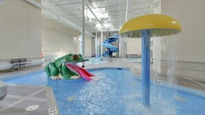 An indoor water park with a large slide, a frog-shaped play area, and a water fountain. - 🍁Mountain Views, Pools, Fitness, Restaurant & MORE, we're accepting bookings! (Canmore)