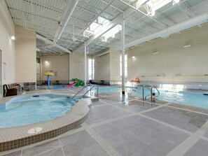 Ein Hallenbad mit Whirlpool, Rutschen und einem Rettungsschwimmerstand.