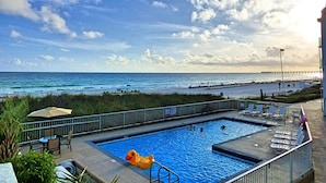 A swimming pool with a lifeguard chair, lounge chairs, and a view of the ocean. - Pet Friendly Ground Level Steps to the Sand! Pool Hot Tub WIFI (Panama City Beach)