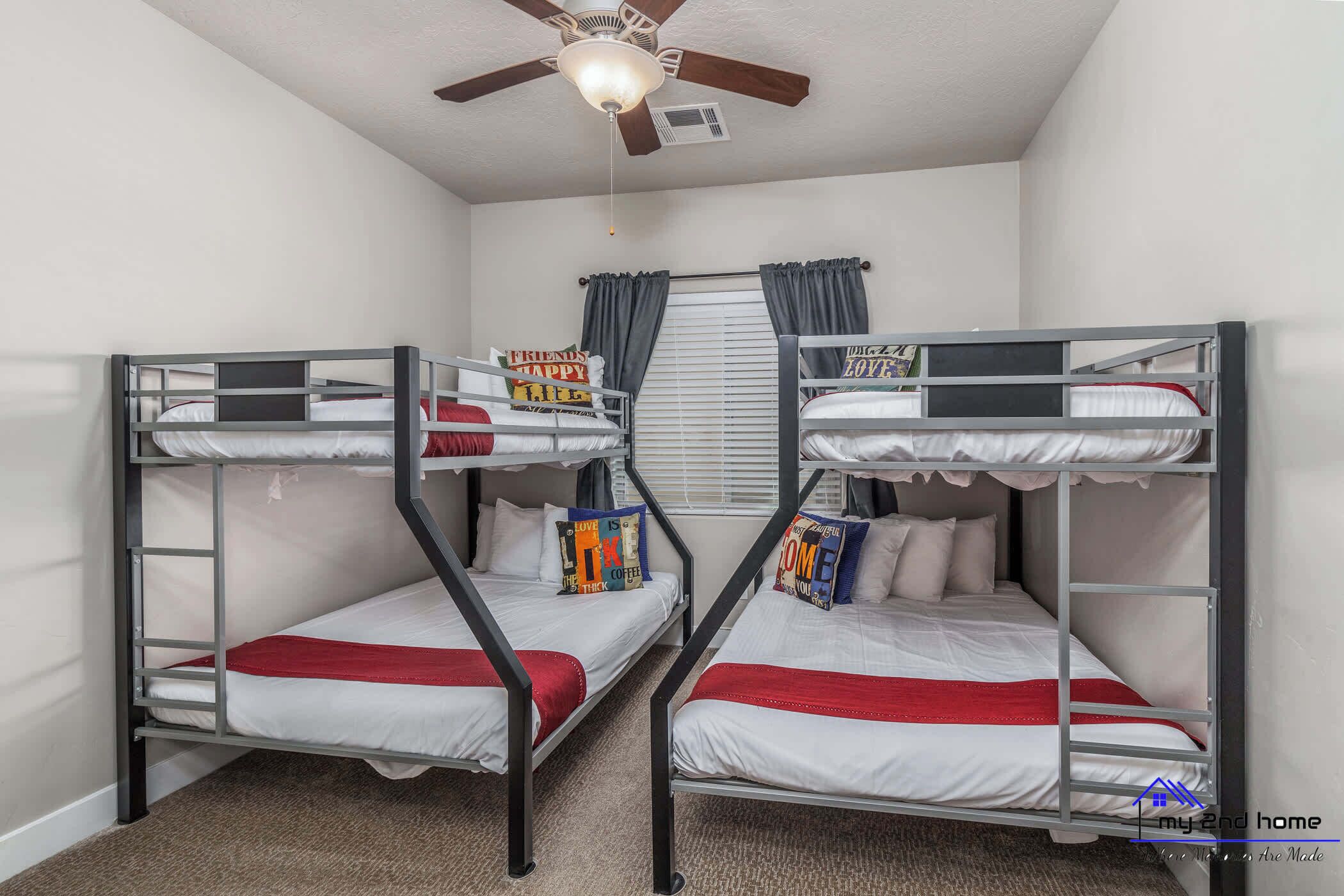 A room with two bunk beds, a ceiling fan, and a window with curtains.