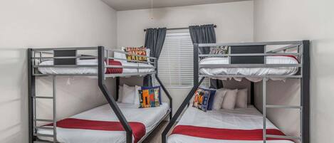 A room with two bunk beds, a ceiling fan, and a window with curtains.