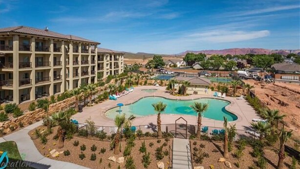 A hotel with a pool area, including a large pool and a smaller pool, surrounded by palm trees and a desert landscape. - Estancia S304 Poolside Getaway Pool (St. George)