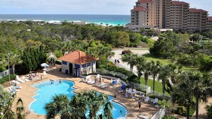 Un resort con una piscina grande, sillas de descanso y vista al océano.