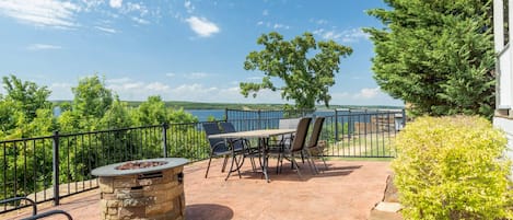An outdoor patio with a stone fire pit, metal chairs, and a table.