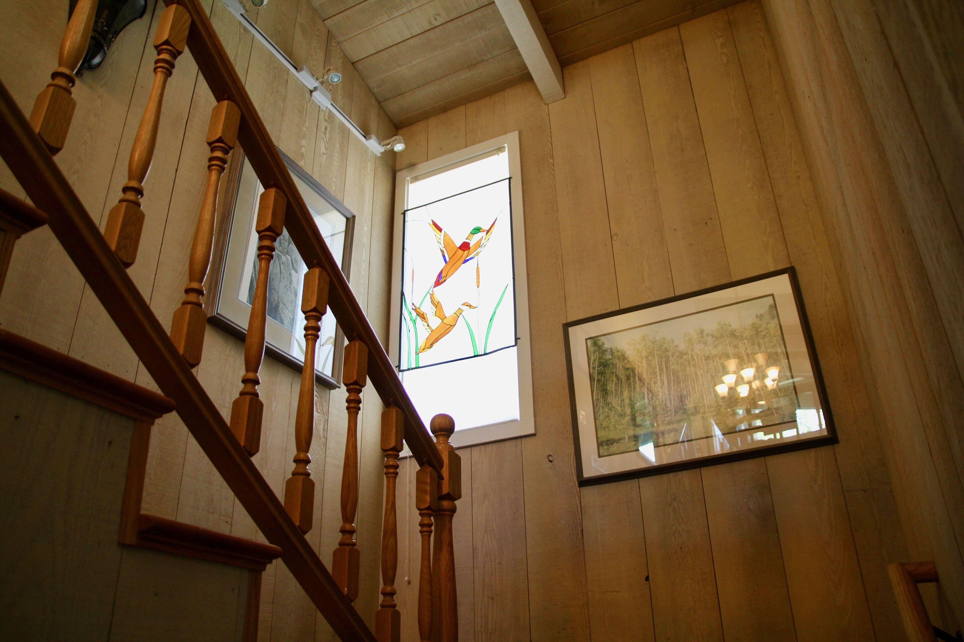 Un escalier en bois avec une fenêtre à vitraux au-dessus.