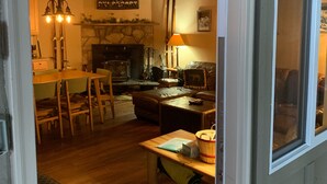 Ein gemütliches Wohnzimmer mit Kamin, Holzmöbeln und einem Essbereich mit Tisch und Stühlen.