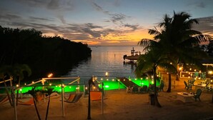 A beachside resort with a pool area, lounge chairs, and a view of the ocean at dusk. - Your Home Away From Home FL Keys Paradise Rental (Key Largo)