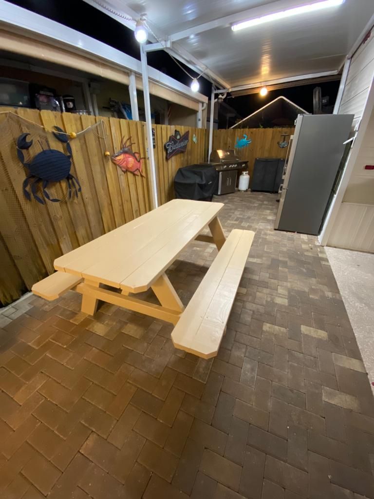 Un patio couvert avec une table de pique-nique et un espace barbecue.