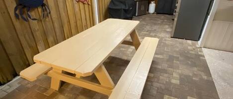 Un patio couvert avec une table de pique-nique et un espace barbecue.