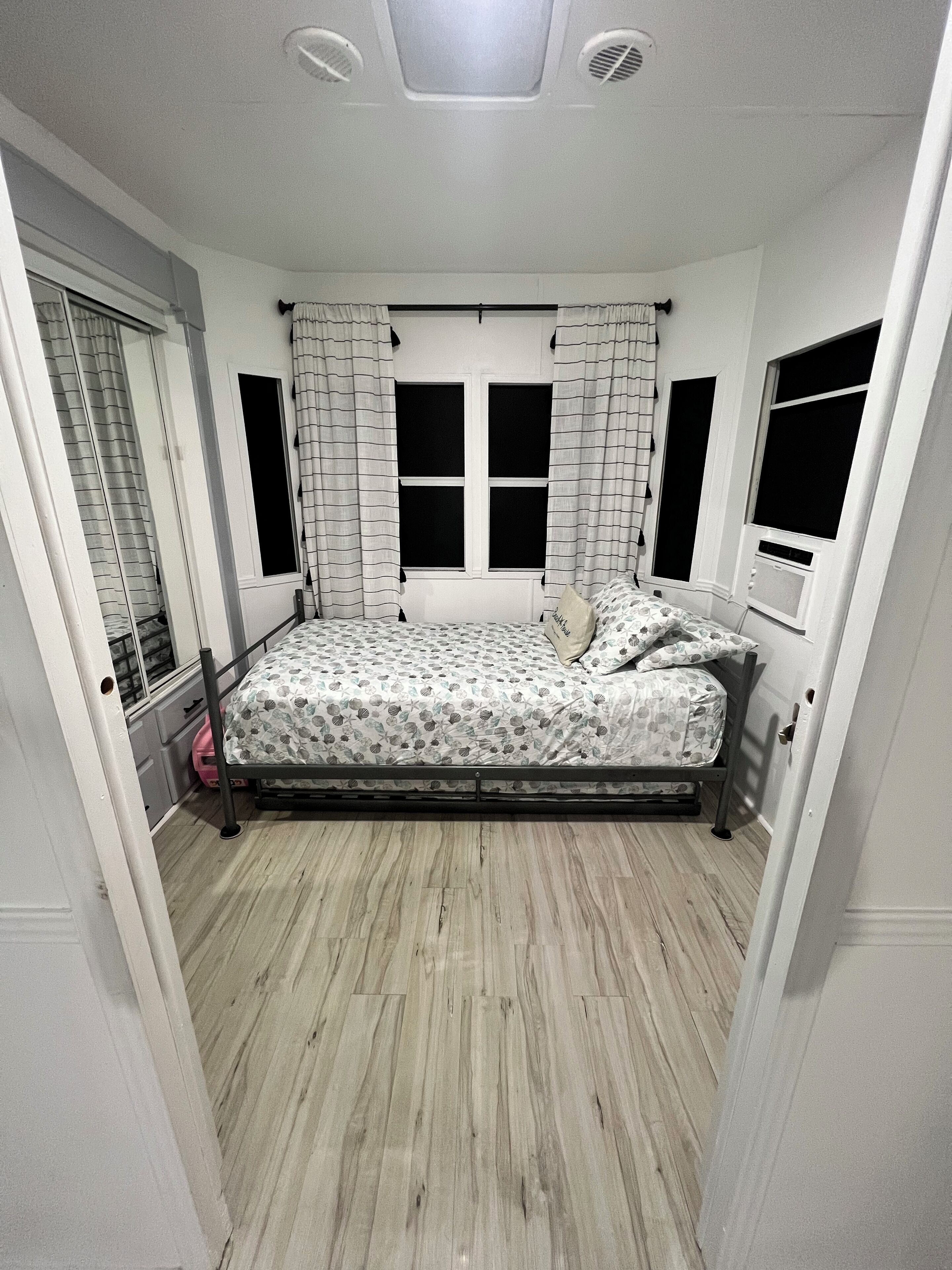 Une chambre à coucher avec un lit, des rideaux, une fenêtre et une porte.