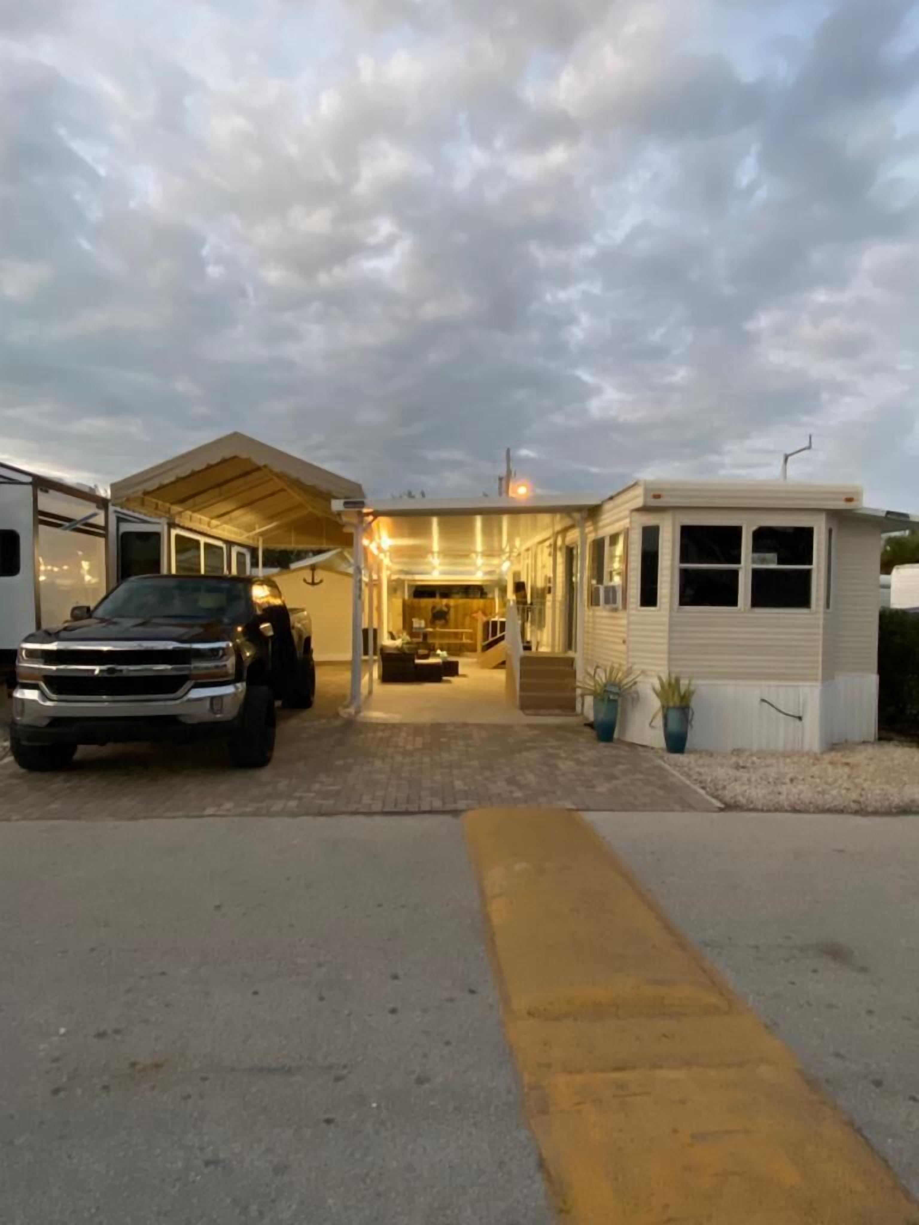A mobile home with a covered driveway and a truck parked in front.