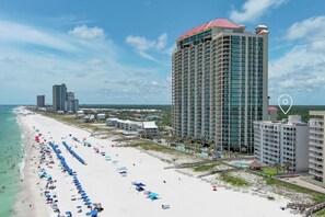 A beachfront hotel with multiple floors, a sandy beach with umbrellas, and a clear view of the ocean. - DIRECT GULF FRONT UNIT, GREAT AMENITIES, CLOSE TO ORANGE BEACH ACTIVITIES (Orange Beach)
