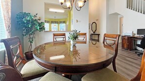 Un comedor con una mesa redonda de vidrio, sillas de madera y una lámpara de araña.