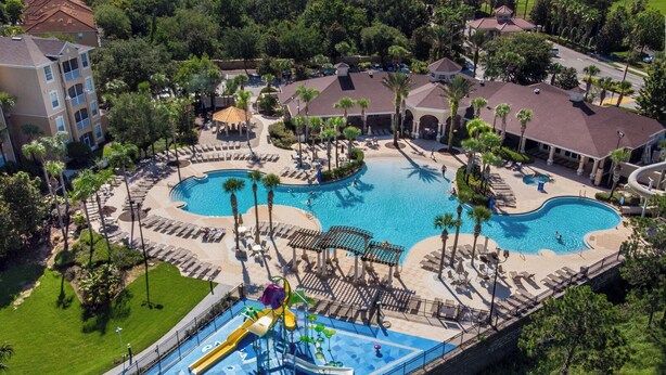 Un resort con varias piscinas, un parque acuático y zonas de descanso rodeadas de palmeras.