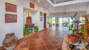 A spacious interior with a high ceiling, a staircase leading to an upper level, and a dining area with outdoor views. - The Best Beachfront villa w/pool, in a secure gated South Akumal community! (Akumal)