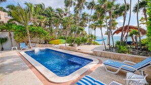 A pool area with lounge chairs, a small pool, and palm trees. - The Best Beachfront villa w/pool, in a secure gated South Akumal community! (Akumal)